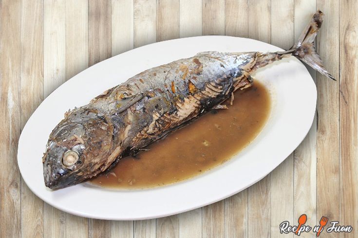 a fish is sitting on a plate covered in gravy