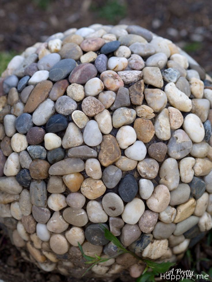 a ball made out of rocks sitting on the ground next to some grass and dirt