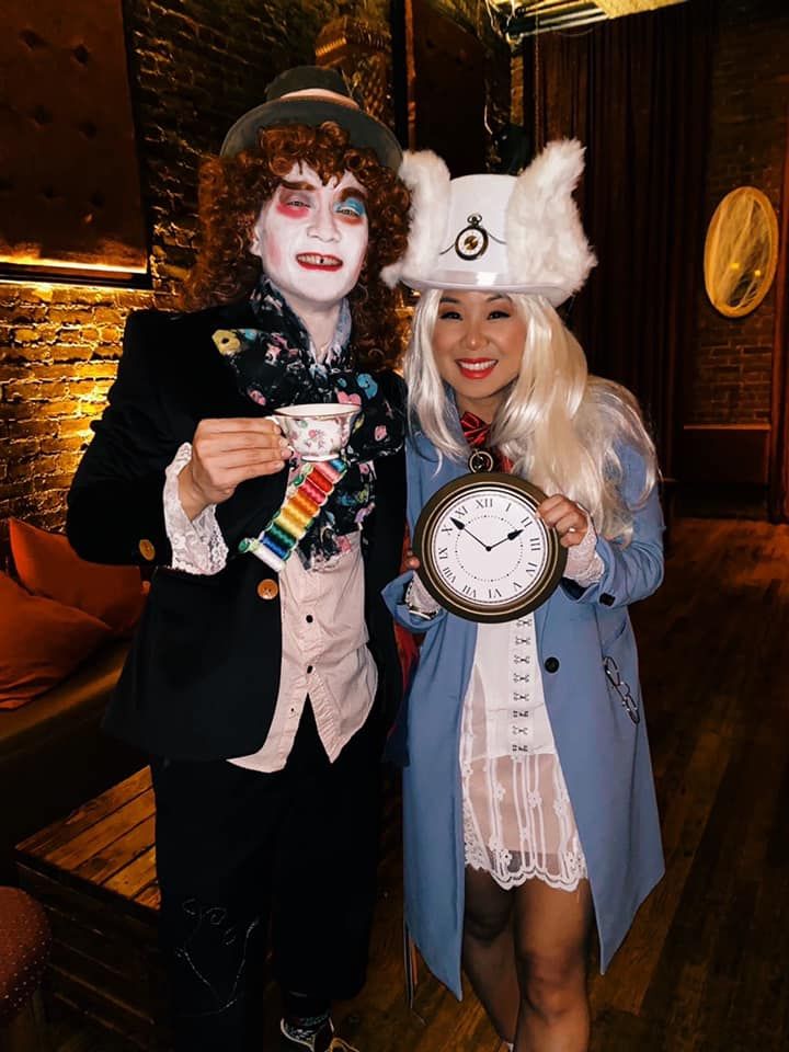 two people dressed up in costumes posing for the camera with a clock on their face