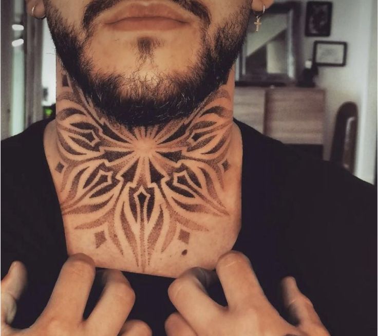 a man is holding his neck tattoo in front of his face and looking at the camera