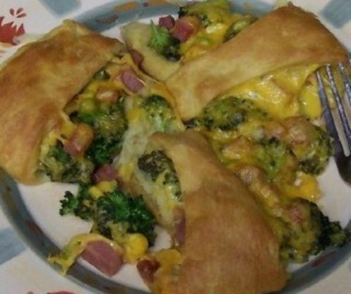 a white plate topped with two pieces of pie covered in cheese and broccoli