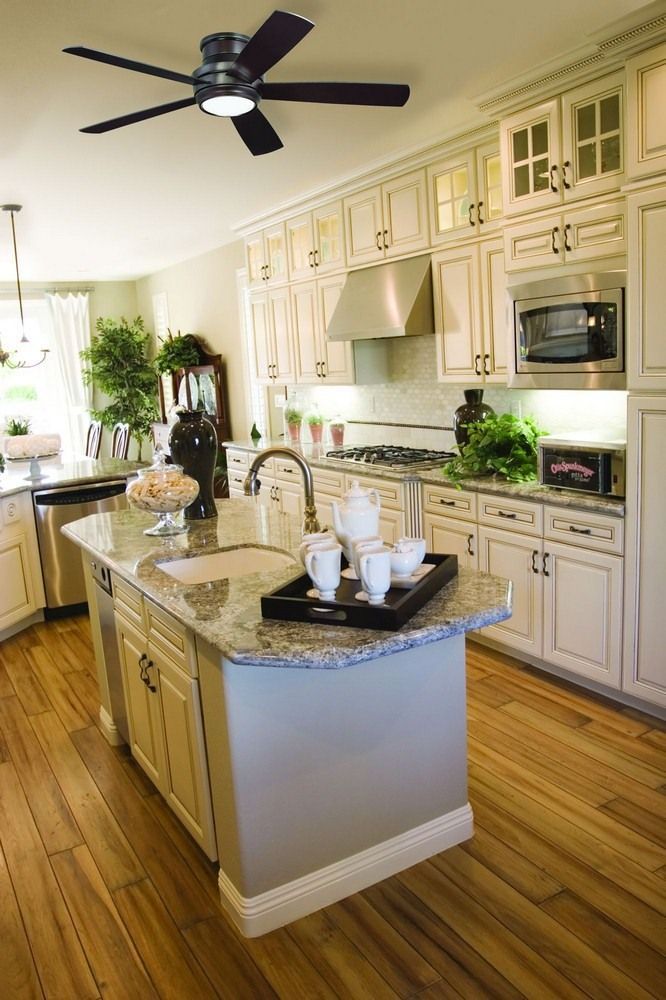 a large kitchen with white cabinets and wood flooring is pictured in this image, the center island has marble counter tops