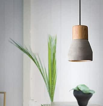 a white table topped with a vase filled with green plants next to a light fixture