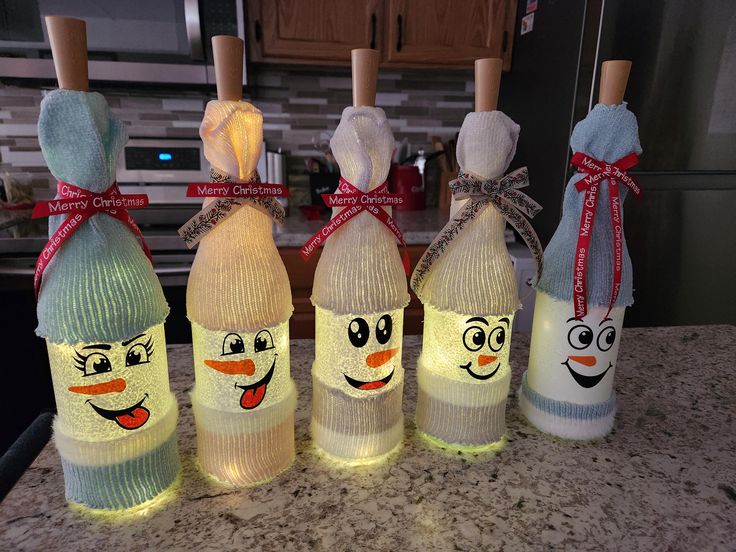 five wine bottles decorated to look like cartoon characters are lined up on a kitchen counter