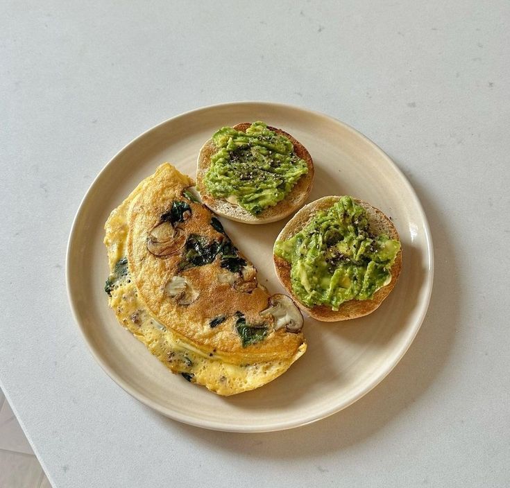 an omelet with mushrooms and spinach on it sits on a white plate