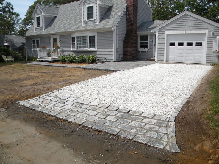 a house that is being built with white gravel on the driveway and two garages