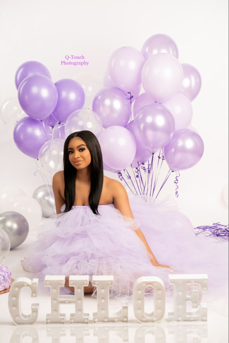 a doll sitting in front of balloons and the word glitlof spelled out