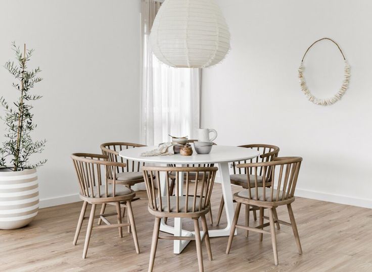 a white table with four chairs and a round light fixture hanging from the ceiling over it