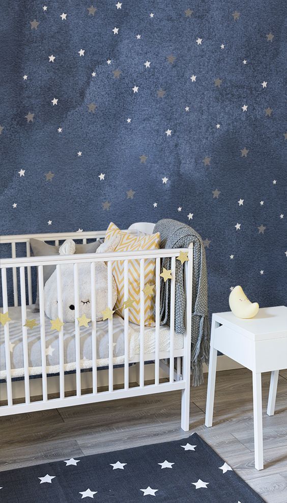 the baby crib is white and has yellow stars on it, along with other wallpapers