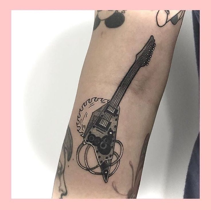 a person with a tattoo on their arm holding a guitar in the shape of a rocket ship