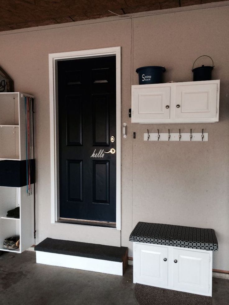 there is a black door and white cabinets in the room with it's bench