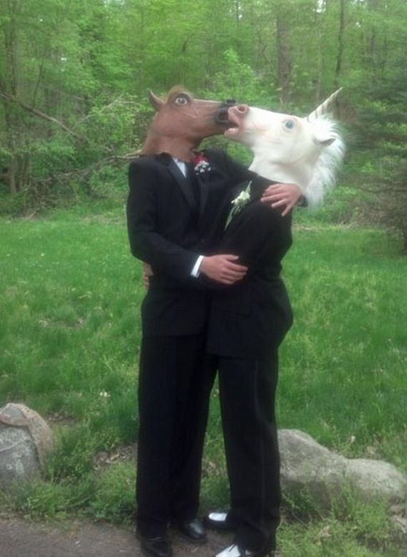 a man in a suit and tie kissing a white dog on the nose with trees in the background