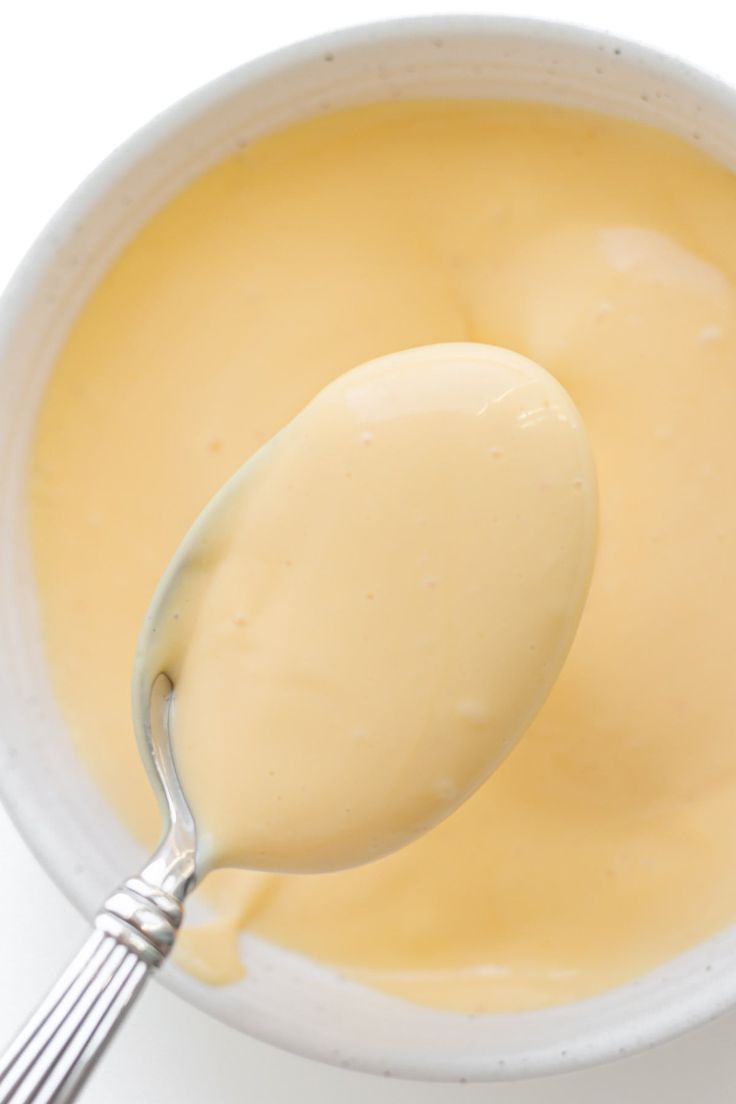 a spoon full of cheese sauce in a white bowl