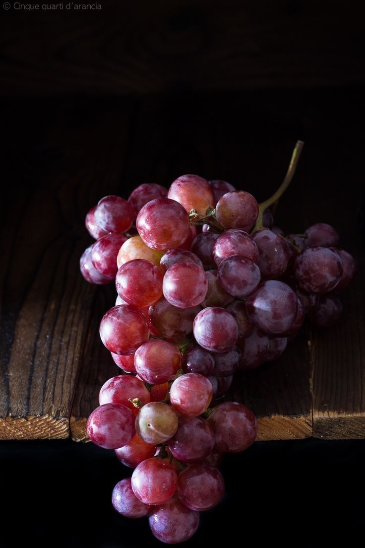 a bunch of grapes sitting on top of a wooden table