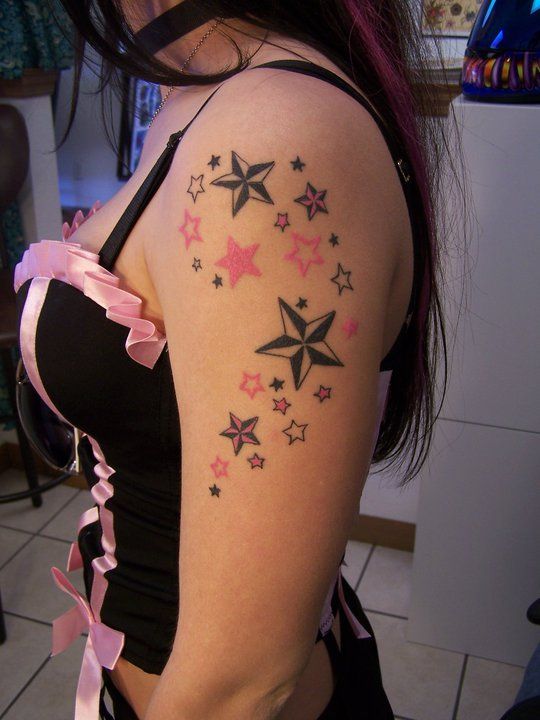 a woman with pink and black stars on her back shoulder, showing the tattoo design