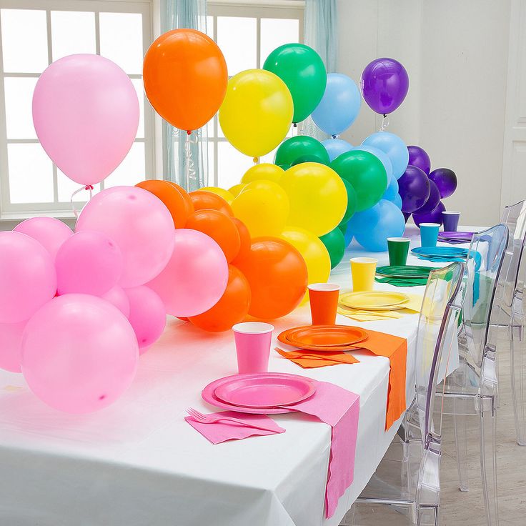 the table is set up with balloons and plates for a party or celebration, it's colorful