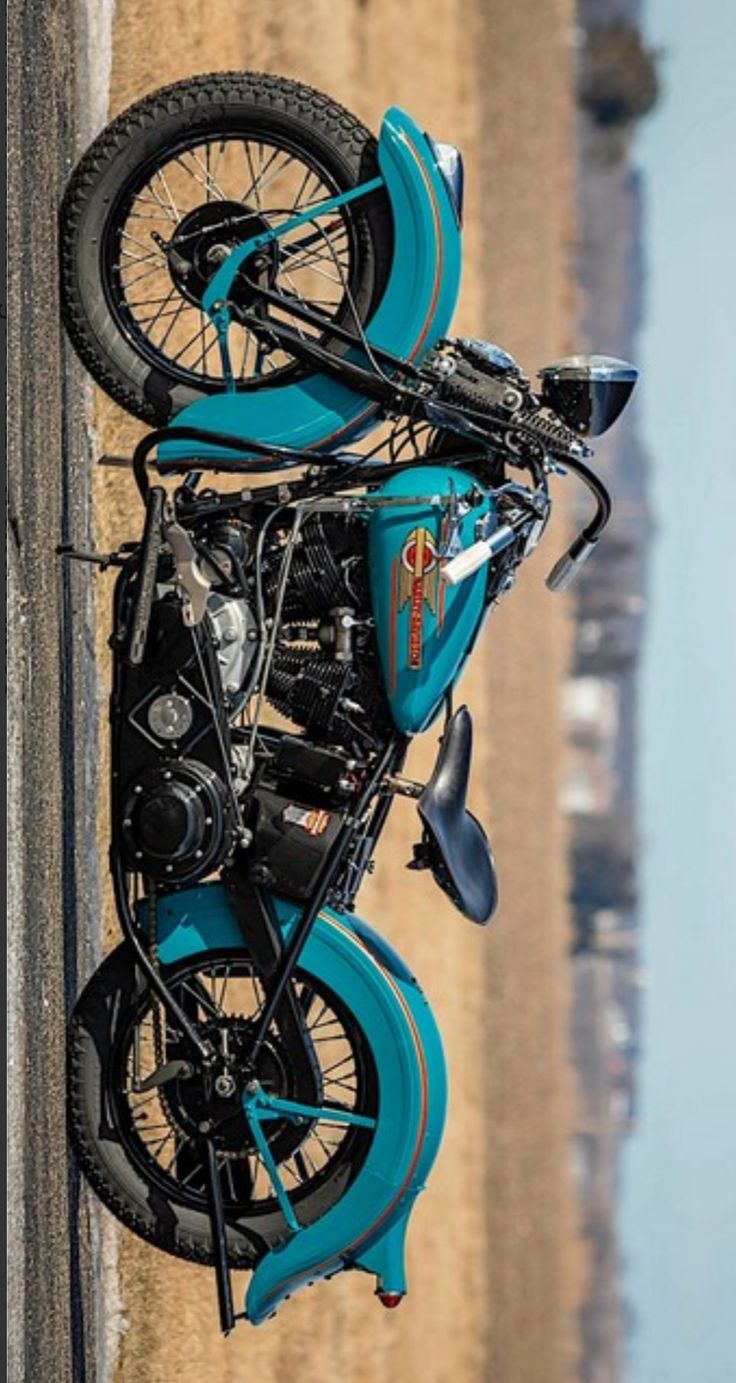 a blue motorcycle parked on the side of a road next to a body of water