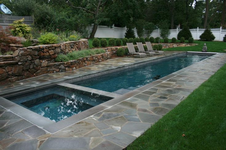 an empty pool surrounded by stone walls and lawn chairs