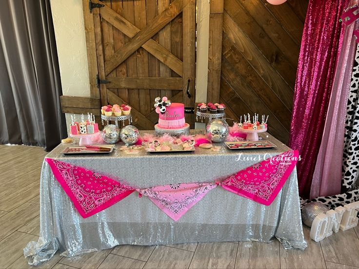 a table with pink and silver desserts on it