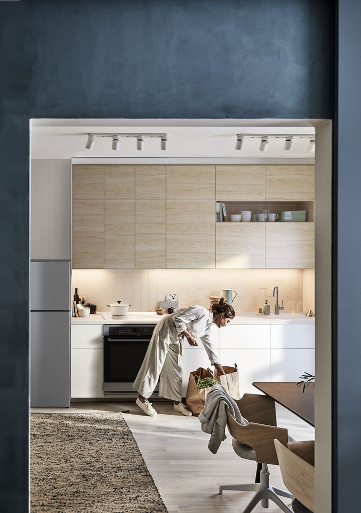 a woman standing in a kitchen next to a table