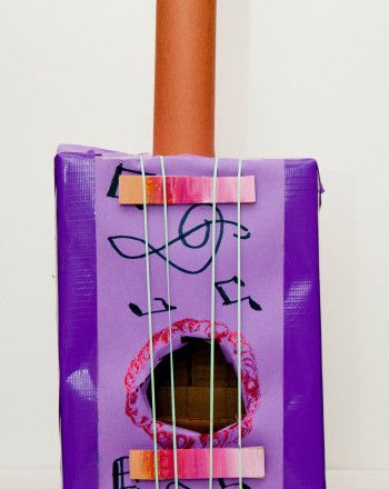 a purple bag with strings attached to it and an orange stick sticking out of the top