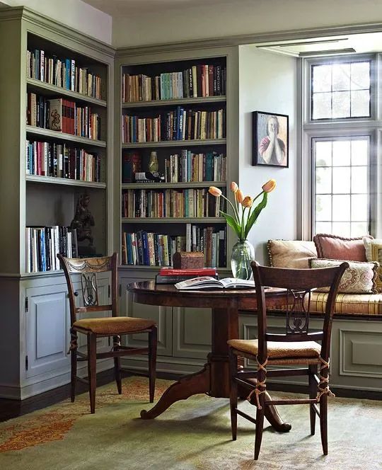 a living room filled with lots of furniture and bookshelves next to a window