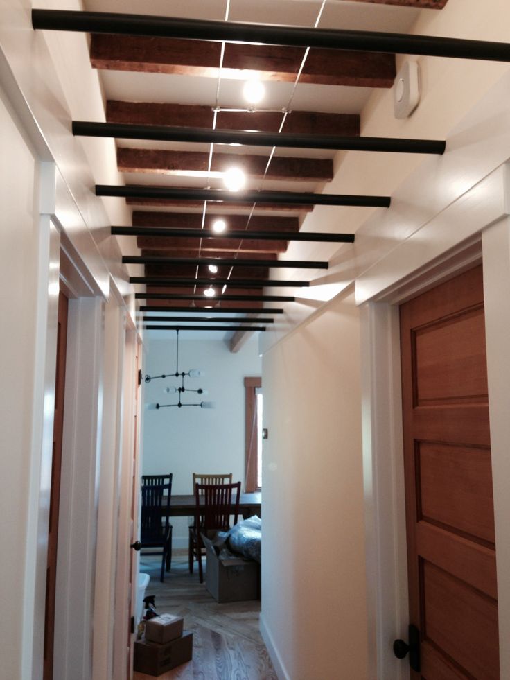 an empty hallway leading to a dining room and living room with exposed wood beams on the ceiling