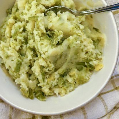 a bowl filled with mashed potatoes and broccoli on top of a table