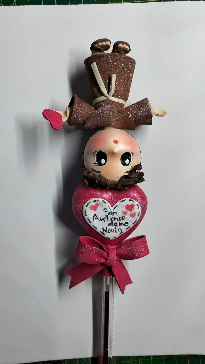 a cake topper that is shaped like a doll wearing a hat and holding a heart