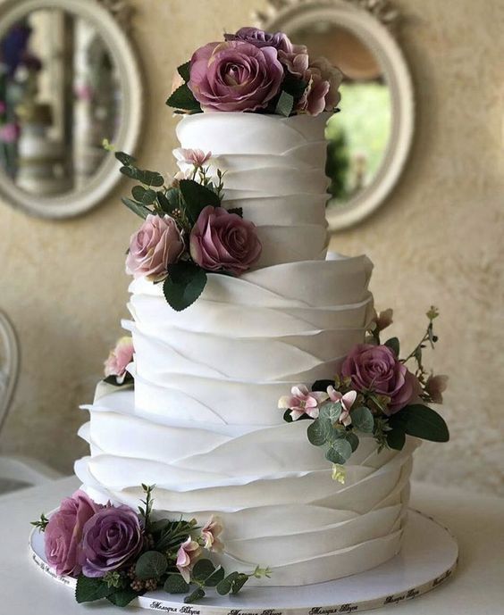 a white wedding cake with purple flowers on top