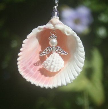 a pink shell with an angel charm hanging from it