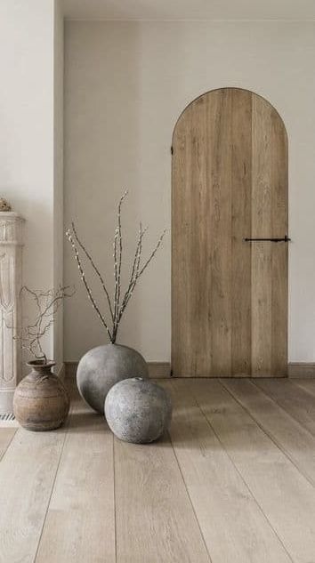 two vases are sitting on the floor in front of a wooden door and fireplace