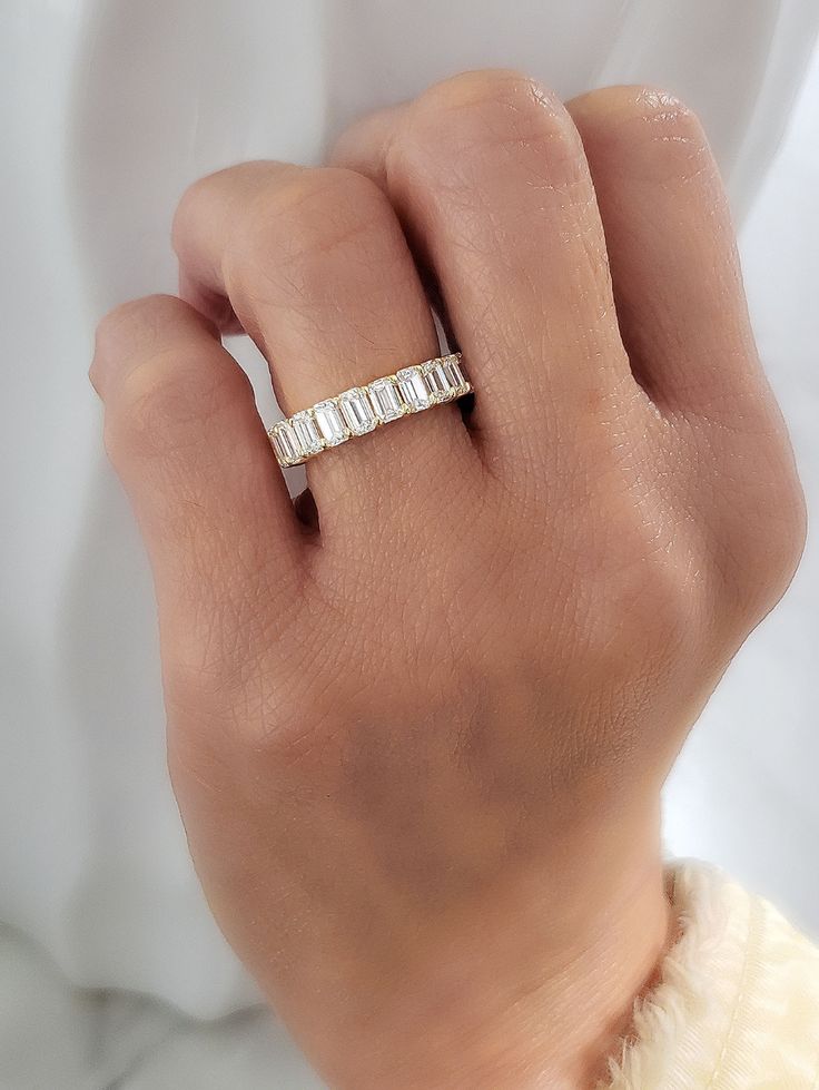 a woman's hand wearing a gold and white ring with three baguettes