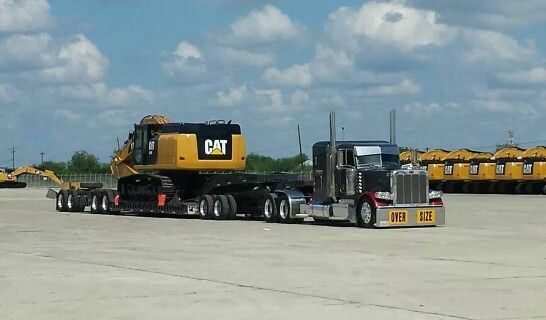 a large semi truck parked in an empty lot with other trucks behind it on a cloudy day