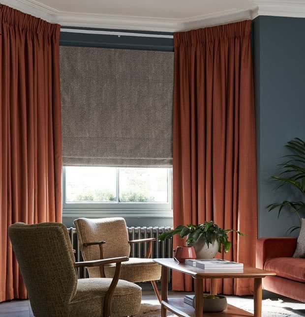 a living room filled with furniture and a window covered in orange drapes next to a wooden coffee table