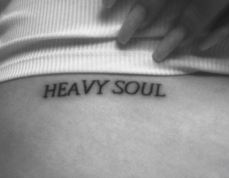 a woman's stomach with the word heavy soul tattooed on her lower back, in black and white