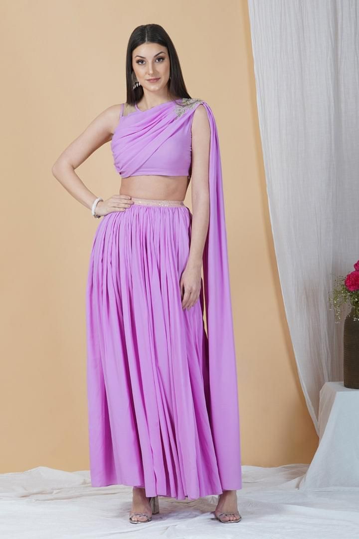 Prep yourself for a dreamy entrance in this beautiful Indo-western outfit that has solid pleated skirt and a blouse. With a bare net back and a drape style blouse, it captures the very essence of sophistication and sensuality in a sheer perfect manner. Having chic silver detailing and lovely drape, it is a perfect choice for that ultra feminine look!Style Indo-western set Elasticated skirt Drapped style blouse Net back Crepe fabric Specifications Model height - 5'9" Model wearing - S Pre-draped Lehenga For Party With Sheer Dupatta, Flowy Pleated Party Skirt, Pre-draped Lehenga With Sheer Dupatta For Party, Pleated Long Draped Skirt For Party, Fitted Chiffon Lehenga For Party, Pre-draped Georgette Lehenga For Party, Summer Party Georgette Blouse, Party Skirt Set With Unstitched Blouse, Party Dress With Unstitched Chiffon Blouse