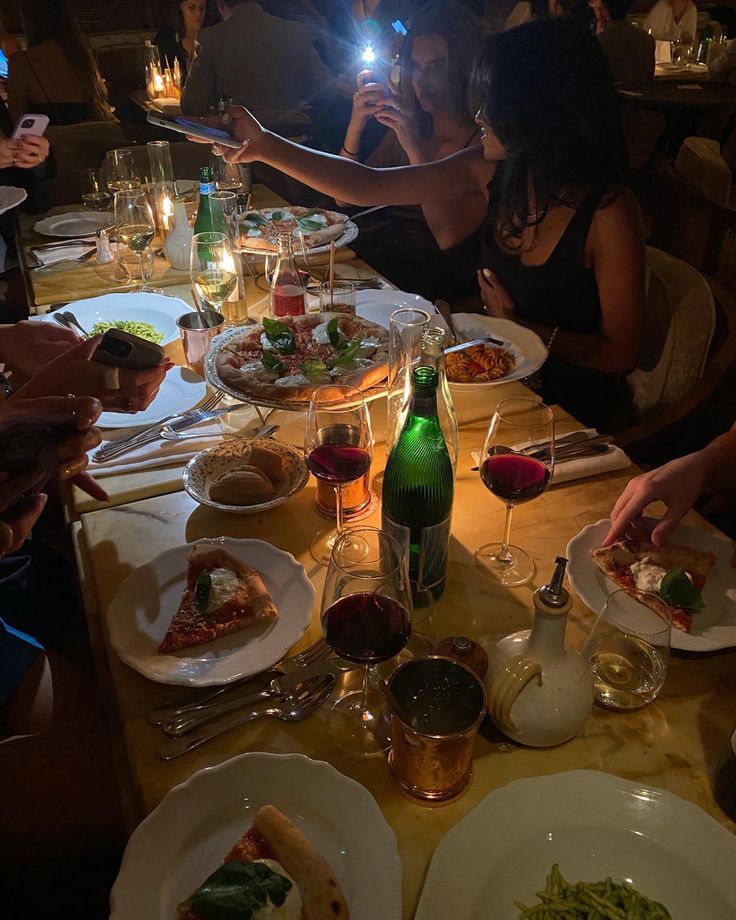 people sitting at a table with plates of food in front of them and one person taking a photo