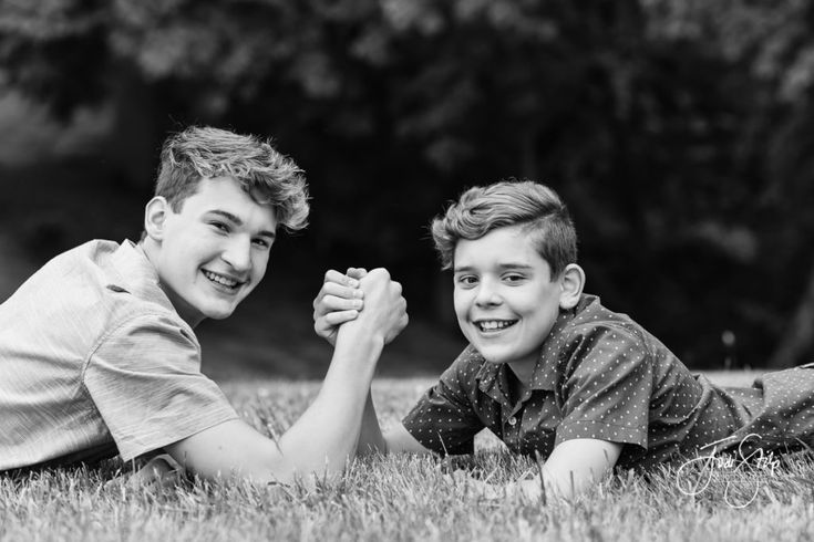 two boys laying in the grass holding hands