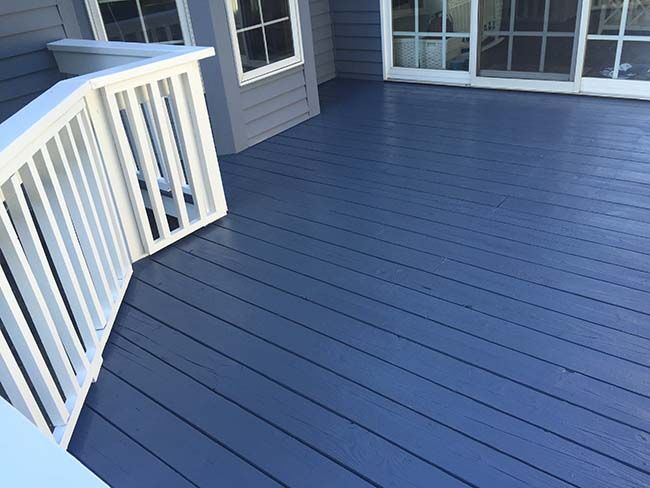 a blue deck with white railing and windows