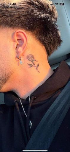 a man with a tattoo on his neck and behind the ear is looking at something