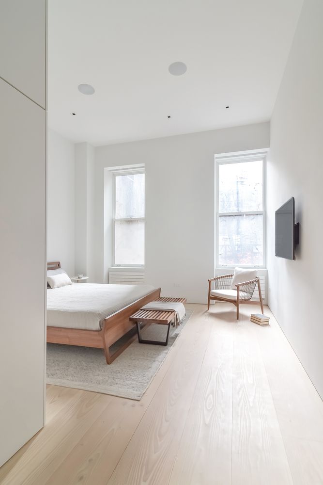 a bedroom with white walls and hardwood floors