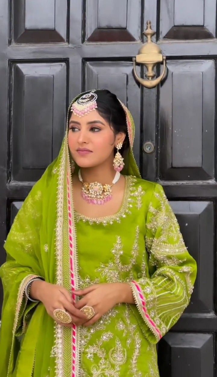 a woman wearing a green outfit standing in front of a door