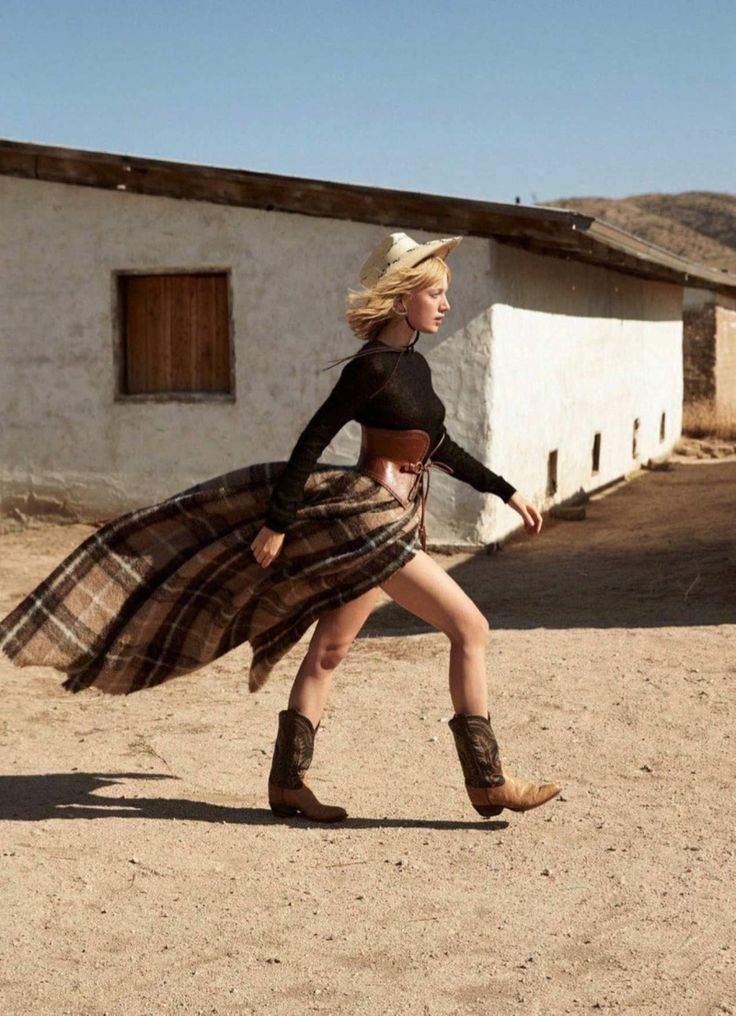 a woman wearing a skirt and boots is dancing in the dirt