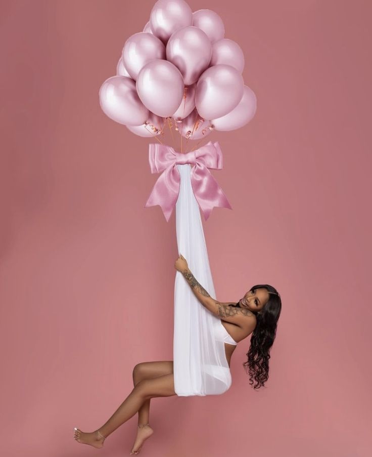 a woman is holding balloons in the air and posing for a photo with her legs crossed