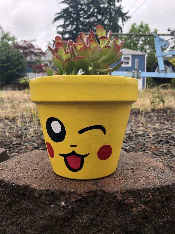 a yellow flower pot with a face painted on it