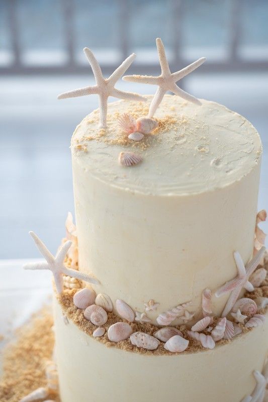 a three tiered cake decorated with seashells and starfish