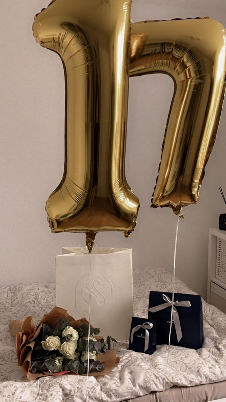 the balloon is shaped like the letter h and sits next to a bouquet of flowers