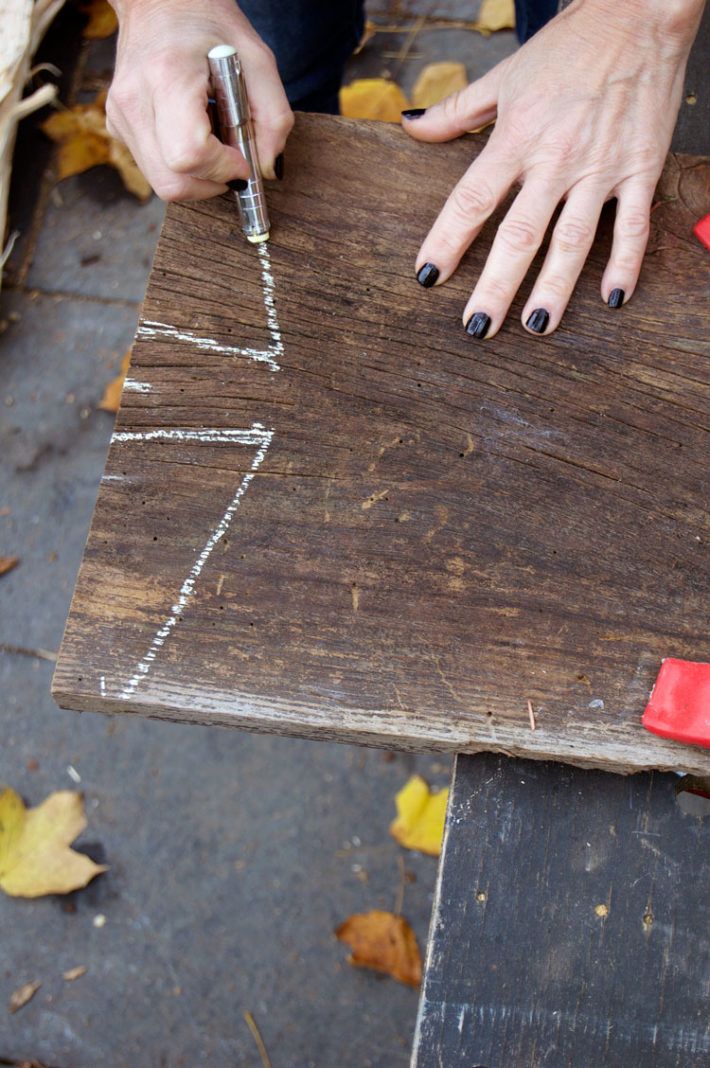 a woman is making a wooden sign out of wood with scissors and glue on it