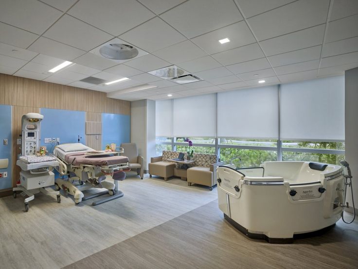 an empty hospital room with medical equipment in the corner and large windows on both sides